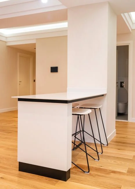 A skilled cleaner, wearing protective equipment, is vacuuming a floor in a contemporary living room.